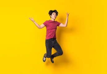 Fototapeta na wymiar Asian man jumping over isolated yellow wall