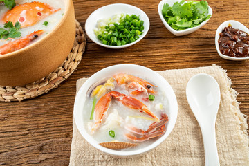Nutritious delicious crab seafood porridge in a bowl on wooden table