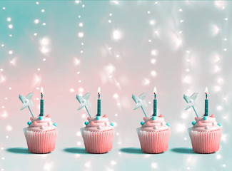Celebratory cupcakes with decorative lit candles on a shiny background
