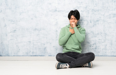 Asian man sitting on the floor is suffering with cough and feeling bad