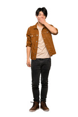 Fototapeta premium A full-length shot of a Asian man with brown jacket covering mouth with hands over isolated white background