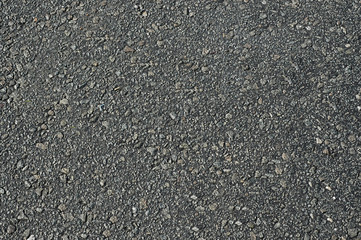 Asphalt roadway with uneven dark gray textured surface .Background