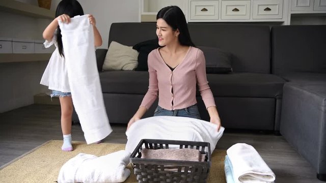 Family concept. Mother and daughter are folding clothes in the basket.