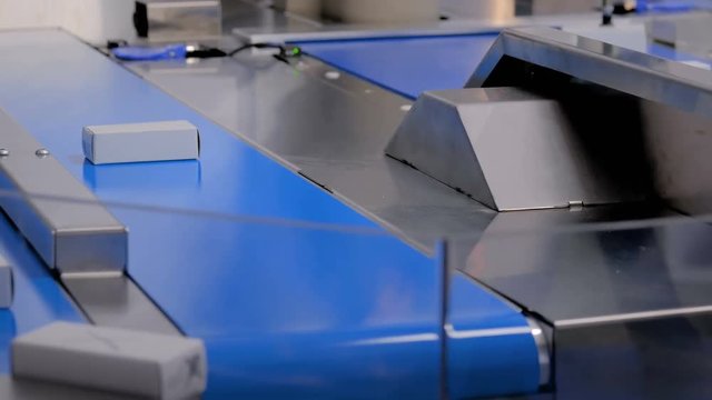 Manufacturing, industry, warehouse system, logistic, package and automated technology equipment concept - automatic production line with moving white small cardboard boxes on conveyor belt at factory