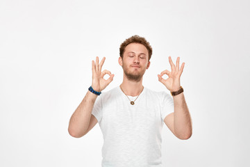 Studio shot of a handsome bearded young man showing gesture of OK expressing emotion of happiness.