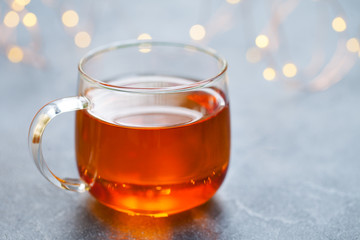Tea in glass cup with light garland. Grey background. Copy space.