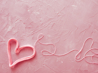 On a coral background heart of coral threads, artistic toning photo.