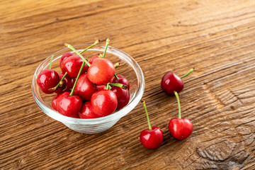 Bowl of fresh red cherries on wooden table