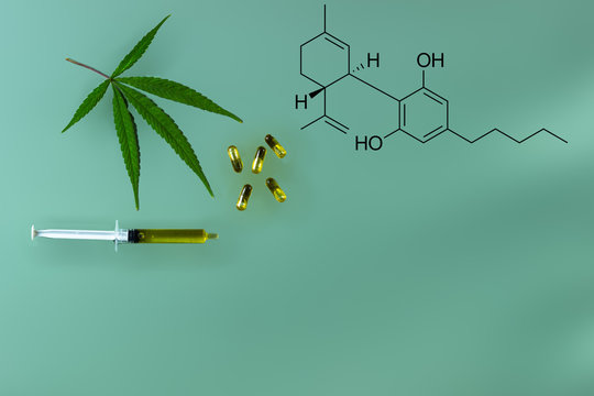 cannabis oil in suringe and capsuals with mariljuana leaf and CBD chemical symbol isolated on green background