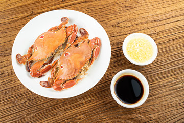 A dish of steamed three-pointed crab and sauce on a wooden table