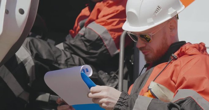 Oil worker makes records in document at oil plant while working