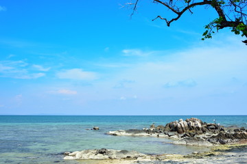 Clear sea, white sand beach, rocks in the sea and blue sky