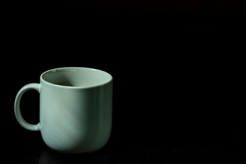 White coffee cup, black coffee on black background with light and shadow