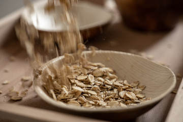 Falling oat flakes in a bamboo bowl