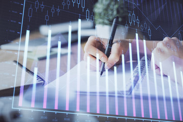 Financial forex graph drawn over hands taking notes background. Concept of research. Multi exposure