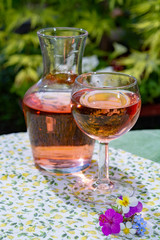 Wine carafe and glass with cold rose wine and wild flowers in summer sunny day
