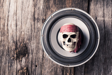 Skull put on a turban with red cloth lay on the old loudspeaker on old wood background