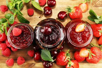 assortment of jams, seasonal berries, cherry, mint and fruits in glass jar