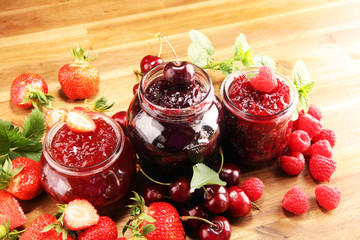 assortment of jams, seasonal berries, cherry, mint and fruits in glass jar