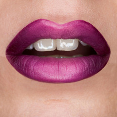 Close-up macro beautiful lips with purple violet mat lipstick. Purple gradient, white teeth and open mouth. Lip art