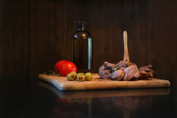 Duck meat with tomatos and olives on a wooden board. Raw rustic food serving.