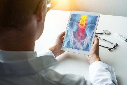 Doctor holding a digital tablet with x-ray of hips with pain on the spine