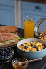 Homemade breakfast. Traditional food. Sandwich, baguette, corn flakes. With sweet berry, honey, muffin. Kitchen. Black table