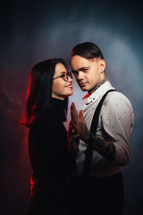 Couple in fashionable clothes on a dark smoky background