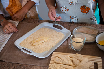 beautiful family at home cooking and having fun together - grandma showing how to cook coockies and fish - indoor lifestyle - caucasian woman and mature woman enjoy