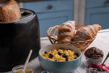 Sweet delicious breakfast. Fresh lunch on kitchen. Corn flakes, croissant, toast with sweet jam. On white table