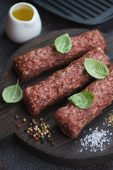 Raw marbled beef kabobs with seasonings on a wooden cutting board, close-up, vertical shot