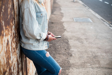 alone girl with phone - girl or teenager with jeans using her smartphone - female holding, playing or working with her mobile