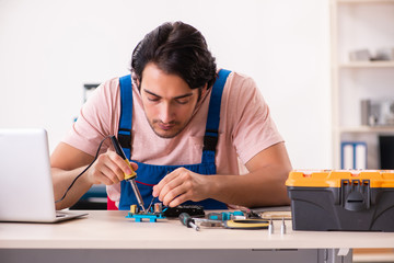 Young male contractor repairing computer  