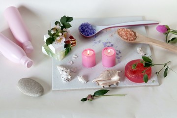 Pink burning candles, flowers, shells, soap, care products on a light background, spa procedures