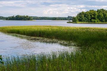 calm countryside lake river with cloud reflections in water and green shores