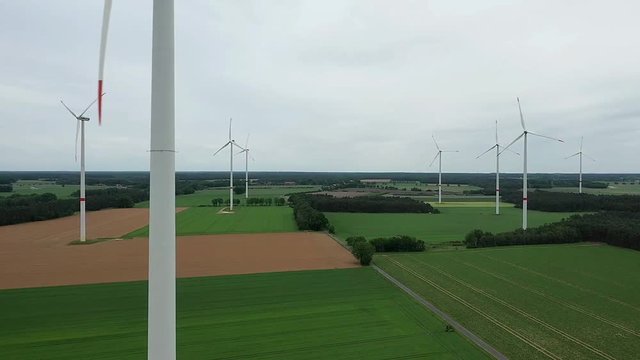 Aerial photograph of the slow pan with the drone camera in front of a wind farm in Germany with wind turbines on the arable land.