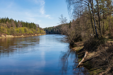 calm countryside lake river with cloud reflections in water and green shores