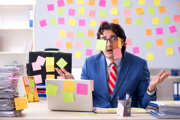 Young male handsome employee in conflicting priorities concept 