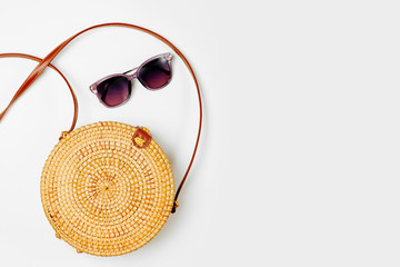 Fashion round bamboo bag and sunglass. Flat lay, top view. Spring/summer fashion concept.