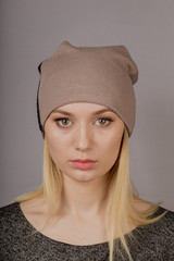 Portrait of a beautiful young girl in a stylish headdress with natural makeup on a gray background.