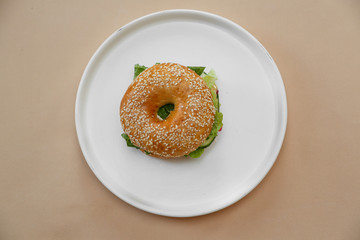 Bagels with cream, avocado, salmon, tomatos on wooden board and table beige background. Healthy breakfast food. Top view