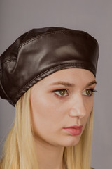 Portrait of a beautiful young girl in a stylish headdress with natural makeup on a gray background.