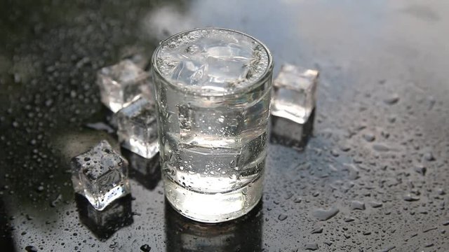 Russian vodka shot with ice on black table
