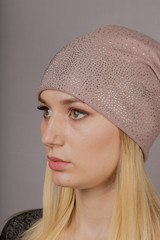 Portrait of a beautiful young girl in a stylish headdress with natural makeup on a gray background.