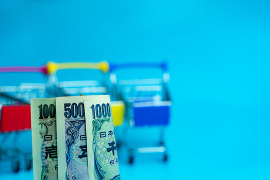 Japanese Yen money rolls with blurry shopping cart space background 