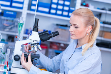 Girl with a slide for the microscope University Hospital. Attractive young scientist  looking at the microscope slide in the forensic laboratory