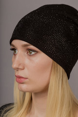 Portrait of a beautiful young girl in a stylish headdress with natural makeup on a gray background.