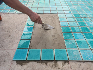 The man hand while using spacer for installing tiles. construction work.Construction Pool.