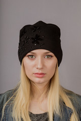 Portrait of a beautiful young girl in a stylish headdress with natural makeup on a gray background.