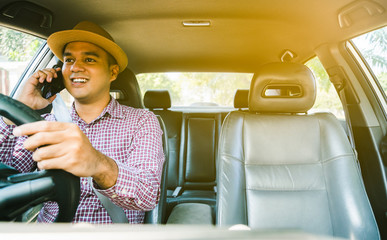 Young asian man using smartphone while driving car